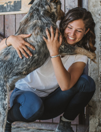 Brunette girl hugging a dog at a barn